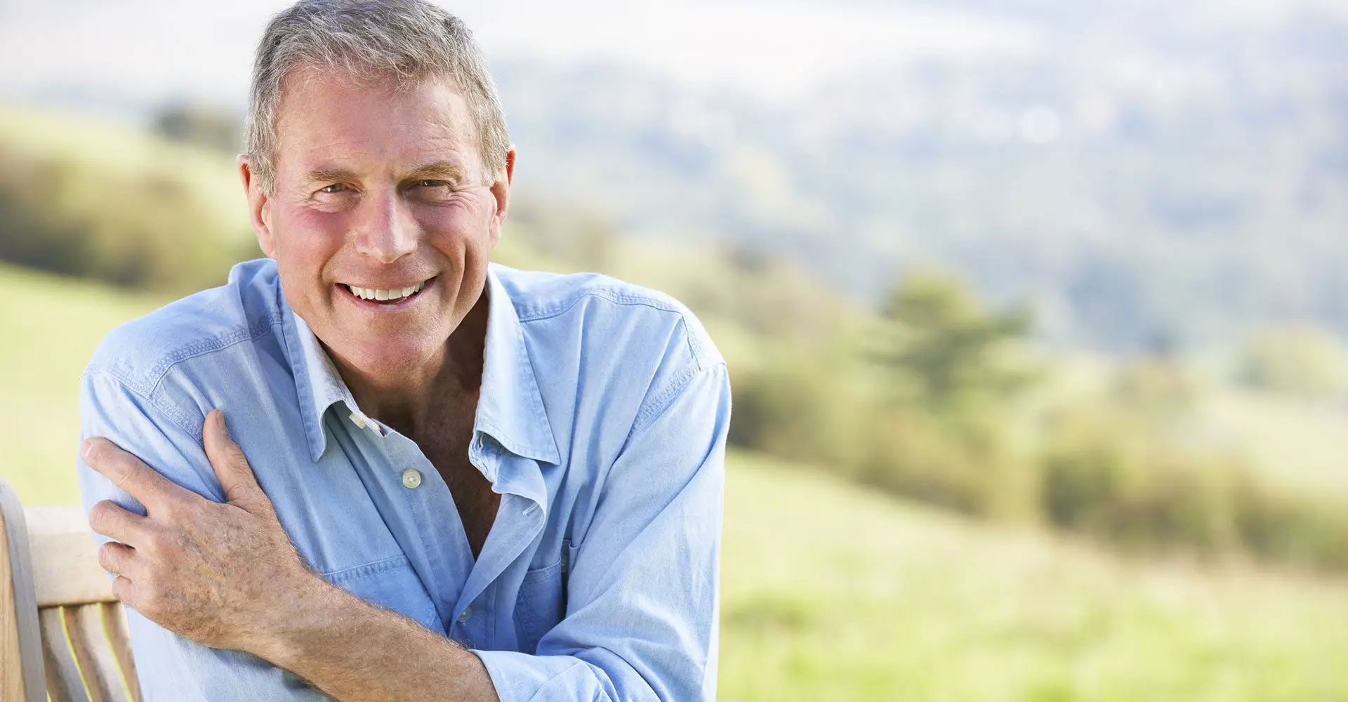 Elderly man smiling because he received a pair of snap-in dentures.