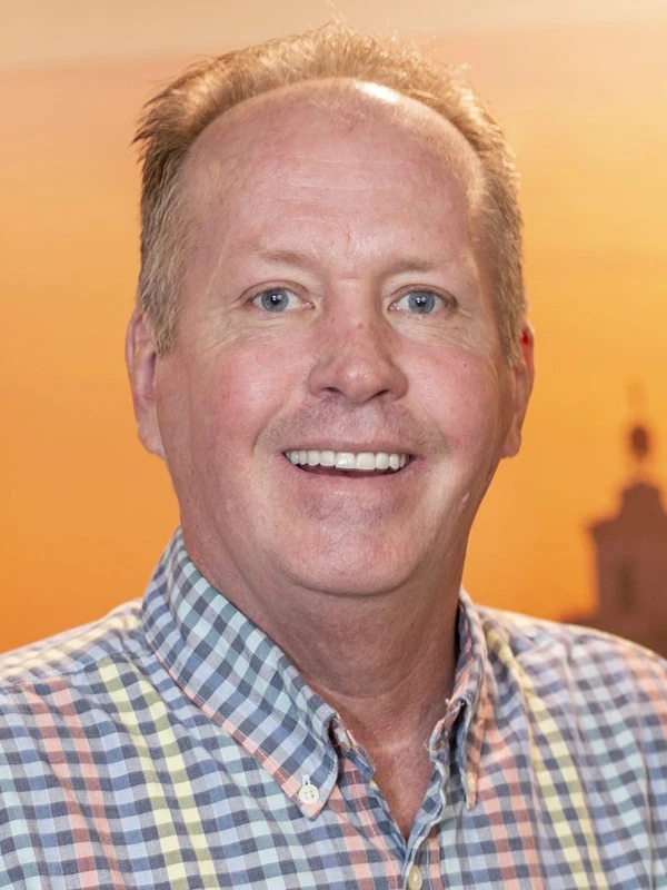 Man in checkered shirt, warm background.